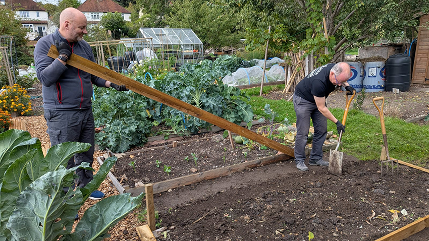 Red Kite's Chief Executive Peter Cogan and Iain Bacon, Interim Chief Finance Officer, adding wooden edging to a vegetable bed at the Grow Together community allotments in Loudwater, High Wycombe