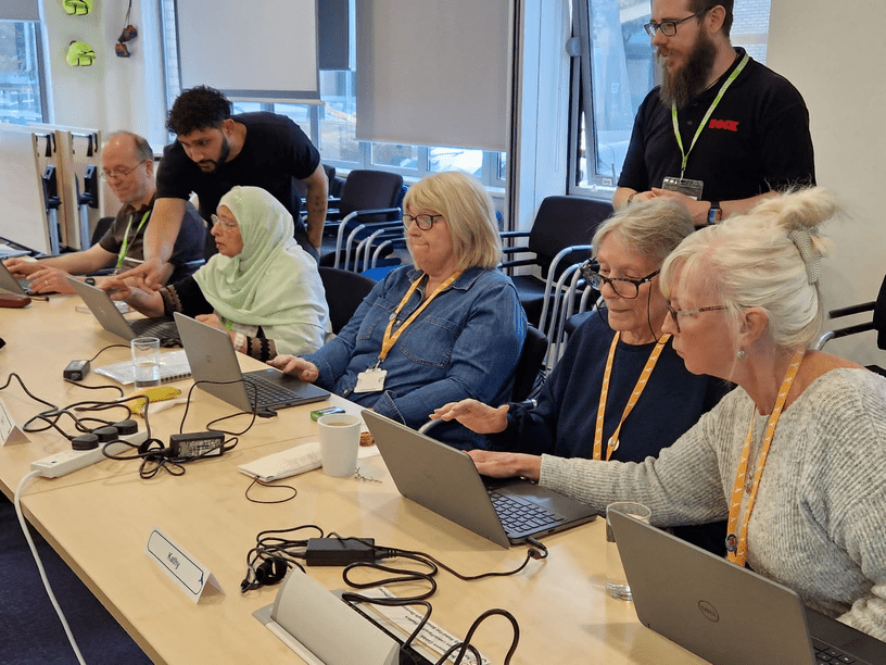 A training session in progress, with tenants using laptops aided by two trainers