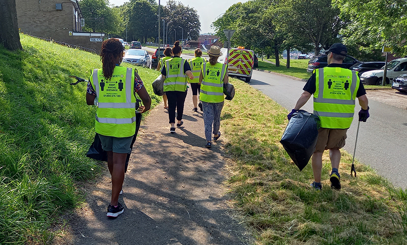 Imbies Estate Blitz - Red Kite staff walking down a road in Downley holding bin bags and litter pickers