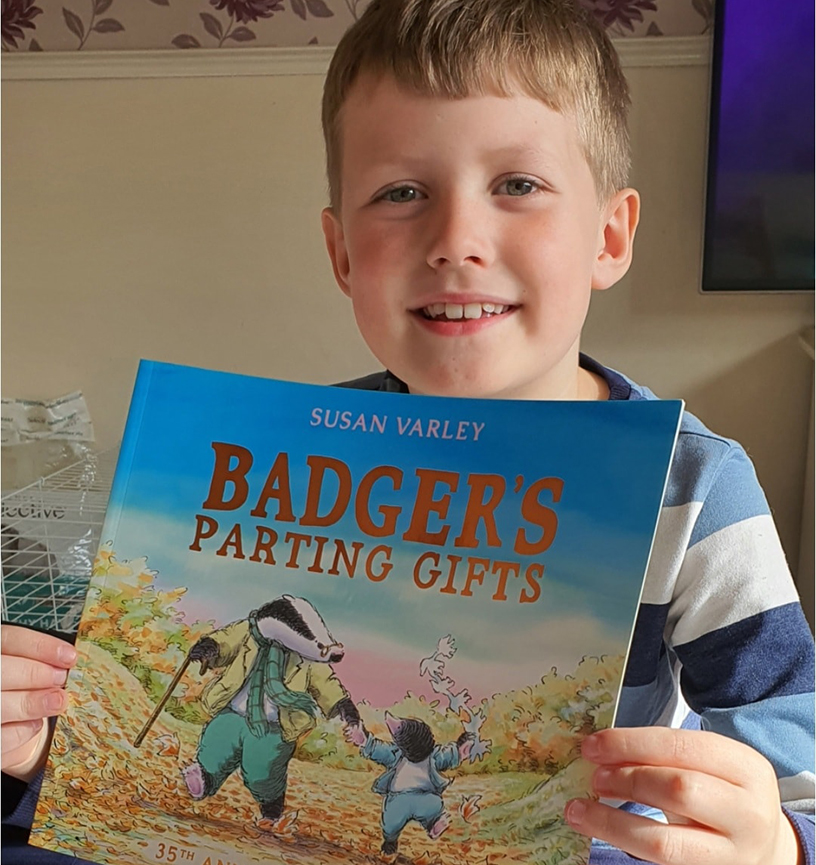 A young boy holding up a book from Memories Box