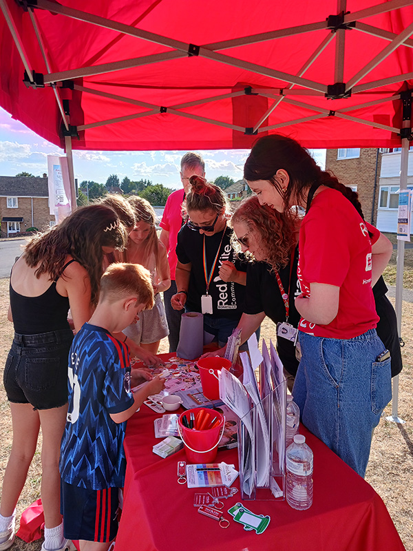 Local Children Looking At Free Gifts On Red Kite's Stall With Red Kite Colleagues