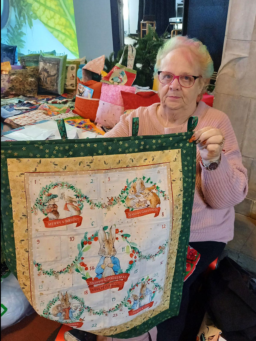 Picture of tenant volunteer, Trish at Christmas fair next to her stall.