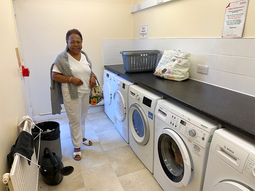 Tenant Smiling In Laundry Room With New Washing And Drying Machines