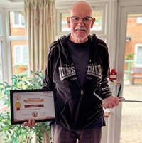 Good neighbour standing with his certificate and medal
