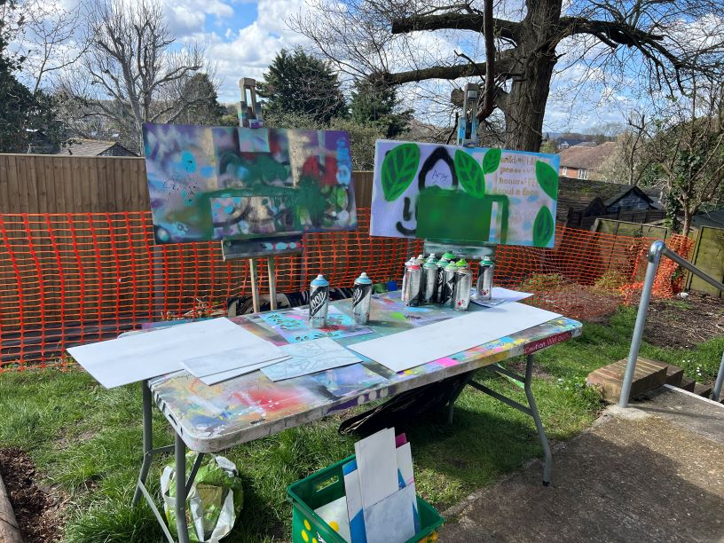 Spray-painted artwork on a table and two easels