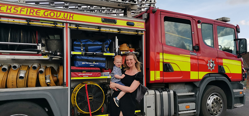 A woman posing with her toddler next to a fire engine