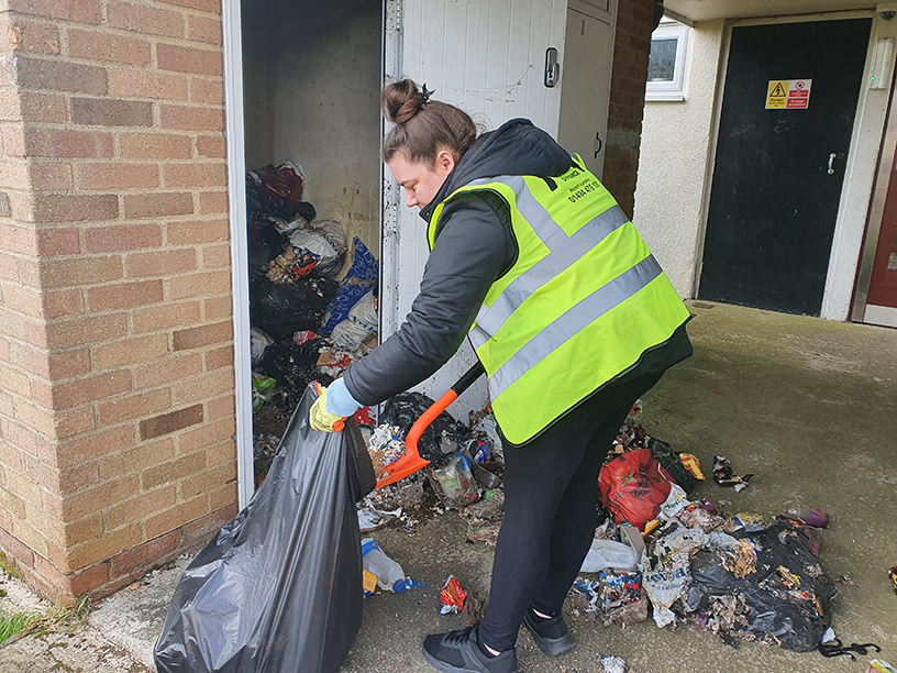 A colleague cleaning the rubbish from a bin shed