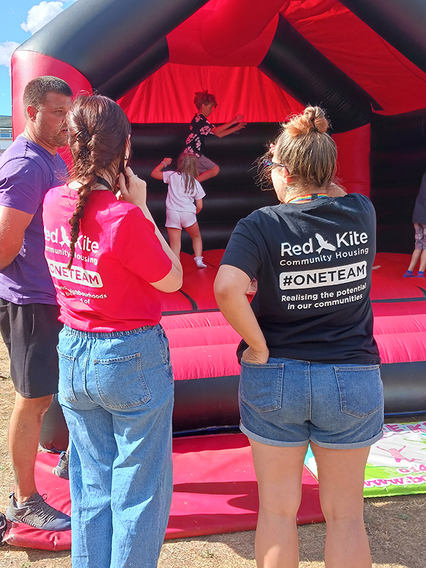 Red Kite Colleagues Chatting With Resident Whilst Children Play On The Bouncy Castle
