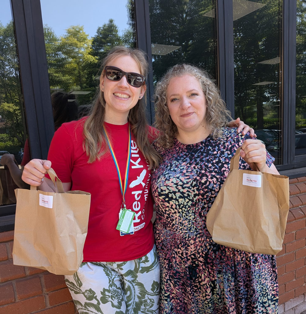 Two members of staff holding brown paper bags