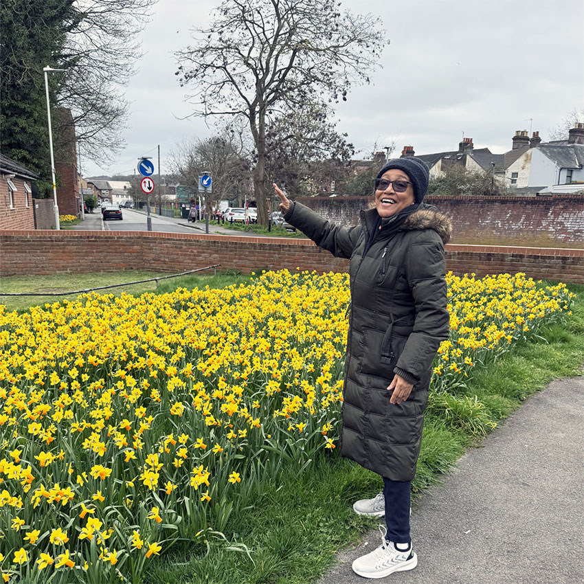 A woman standing next to a row of daffodils