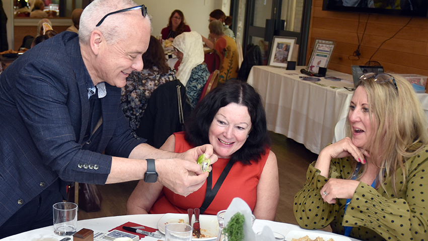 A table magician showing cards to two people sat at a table